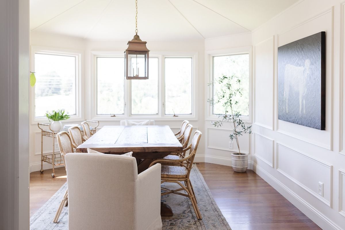 A casual dining room with cream walls and a cream color ceiling, with a wood dining table.