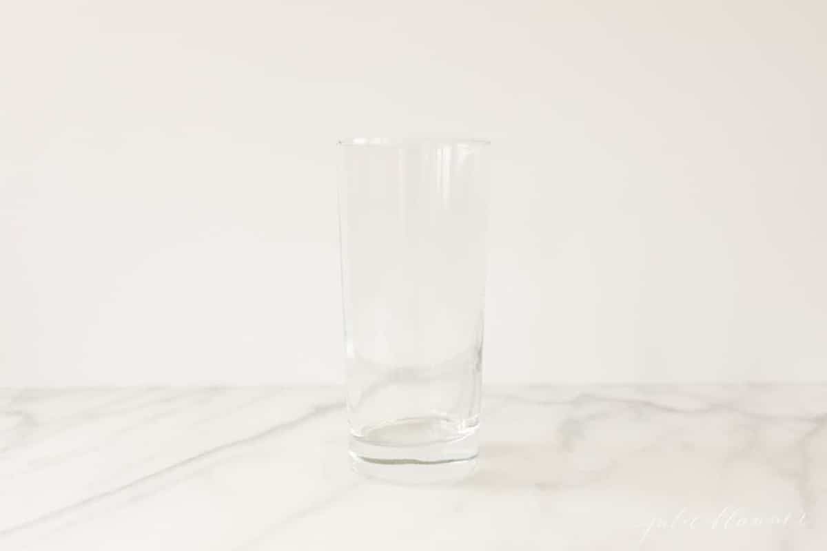 slender clear drink glass on a white marble countertop.