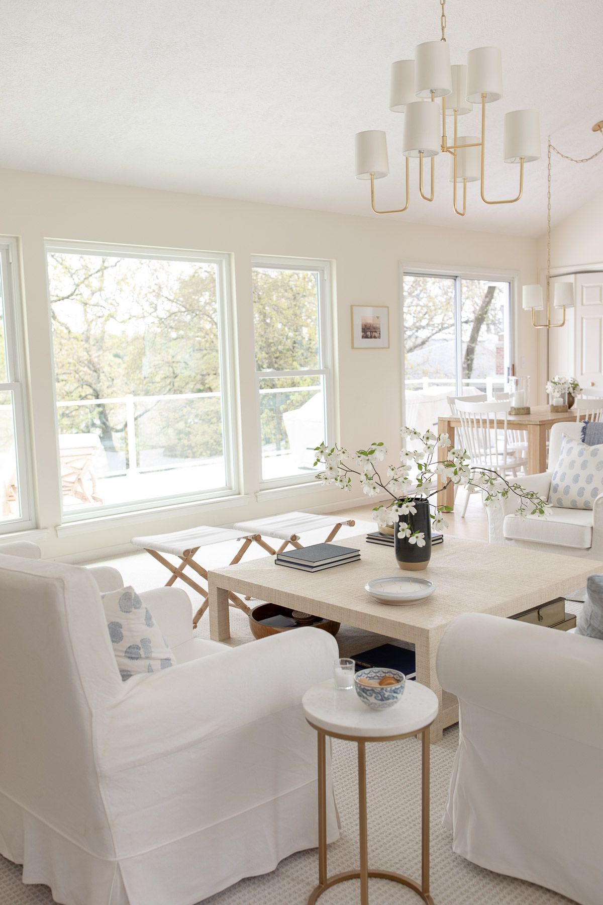 A white living room and eat in kitchen with a brass overhead lighting design