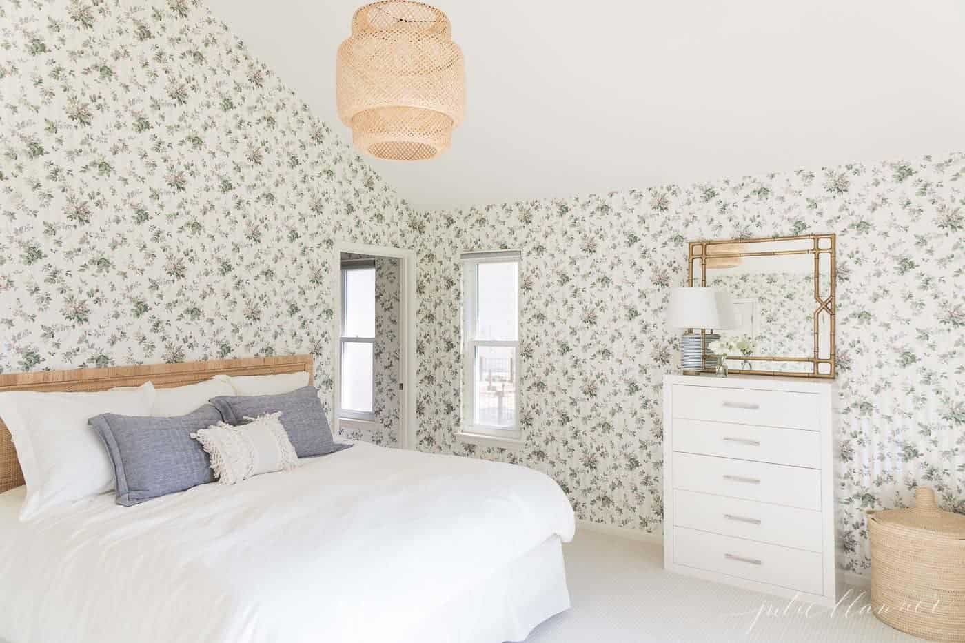 large woven light in a wallpapered bedroom with neutral beddding