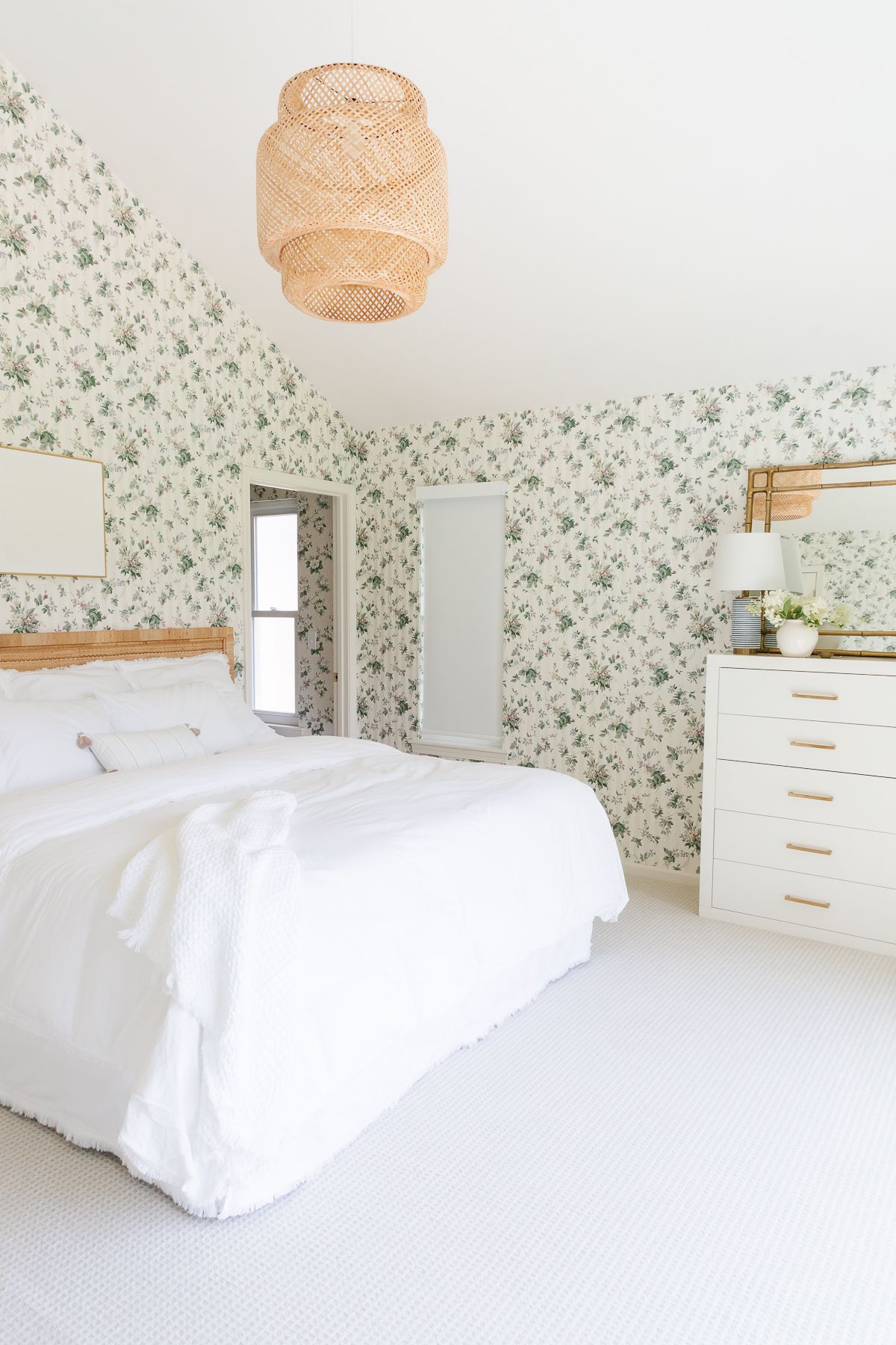 A bedroom with white bedding and floral wallpaper