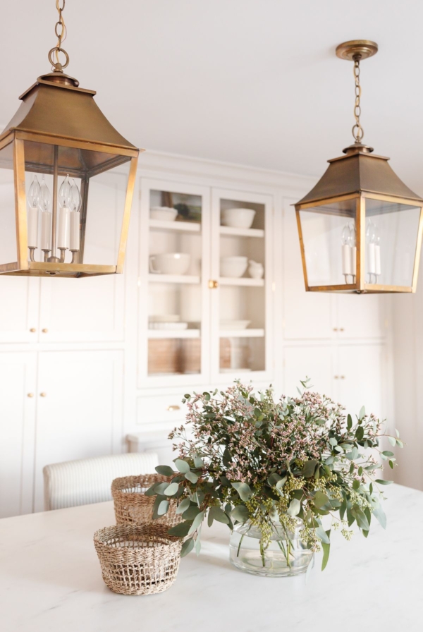 a white kitchen with two brass kitchen island pendants
