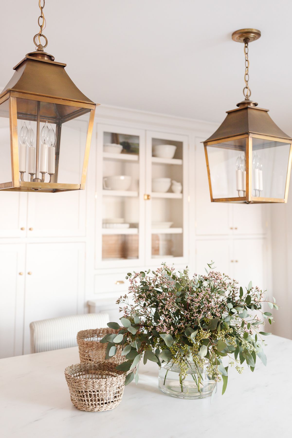 a white kitchen with two brass kitchen island pendants