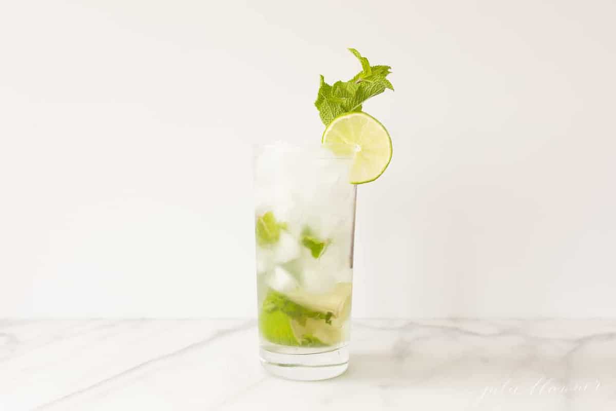 white countertop featuring a tall clear glass with a classic Cuban mojito. 