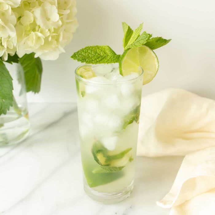 vodka mojito garnished with lime and mint by napkin and flowers