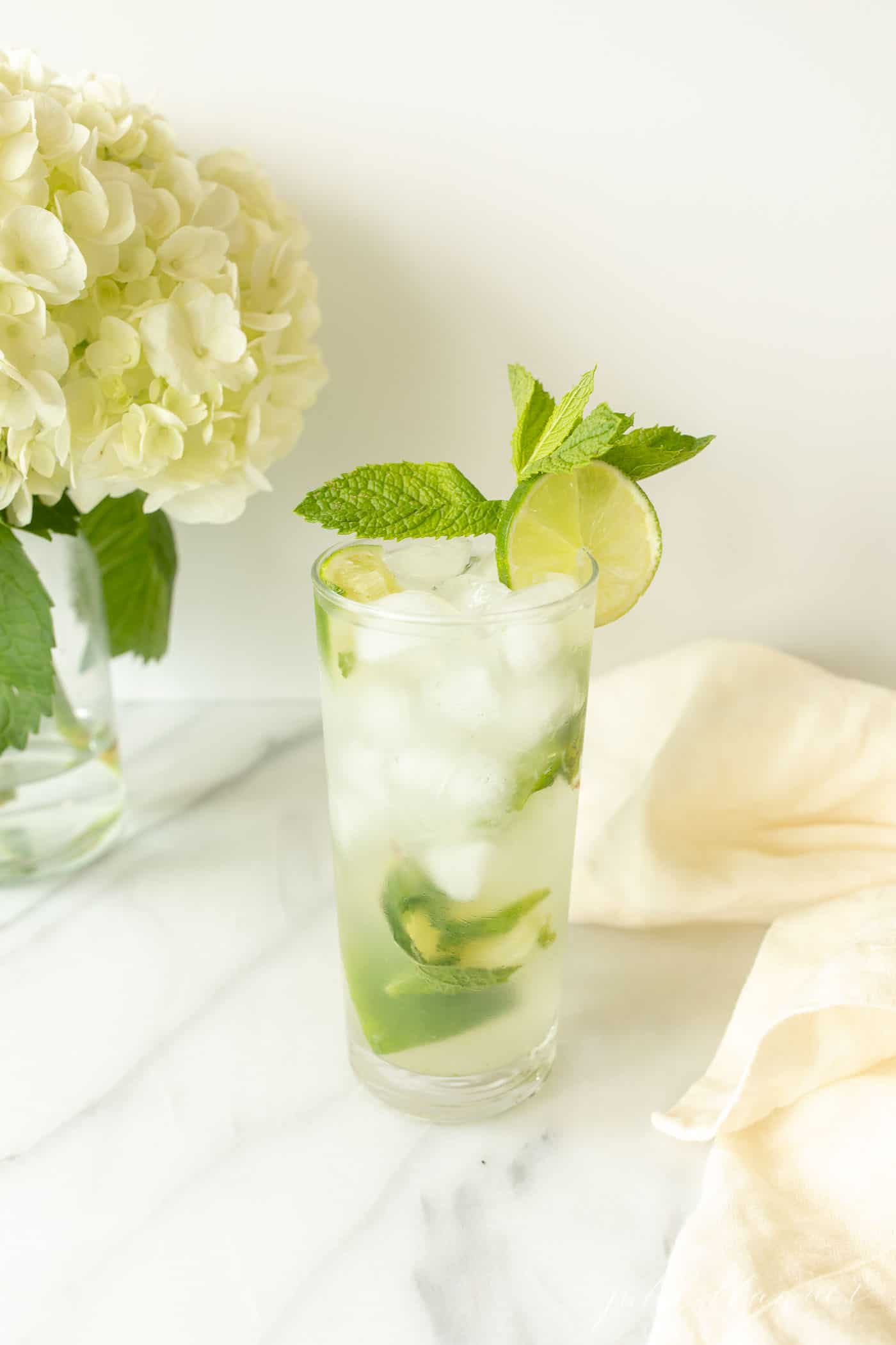 vodka mojito garnished with lime and mint by napkin and flowers