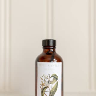 Amber bottle of homemade vanilla extract against a white countertop and background.