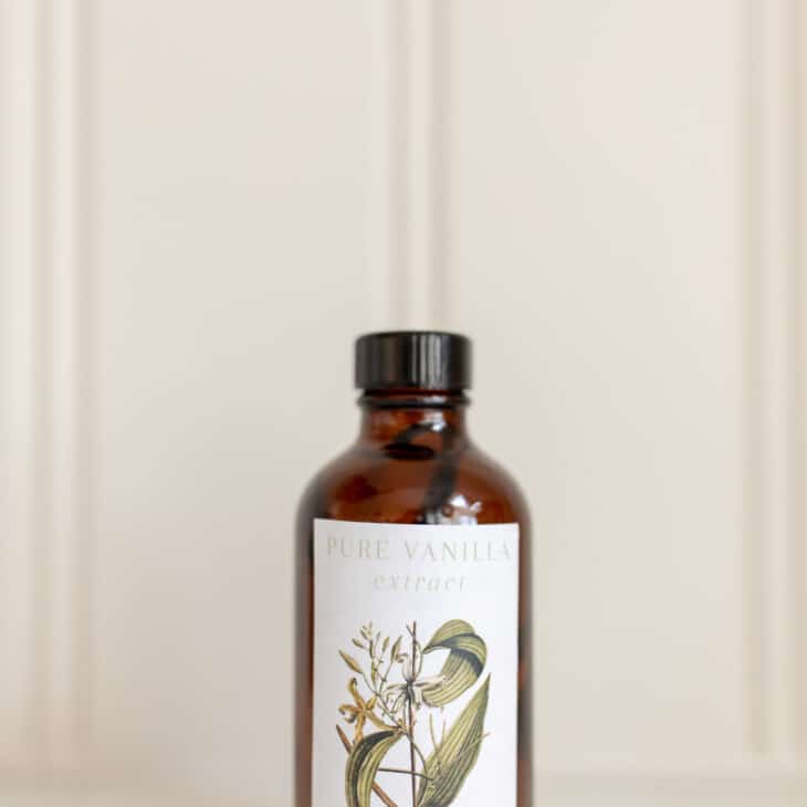 Amber bottle of homemade vanilla extract against a white countertop and background.