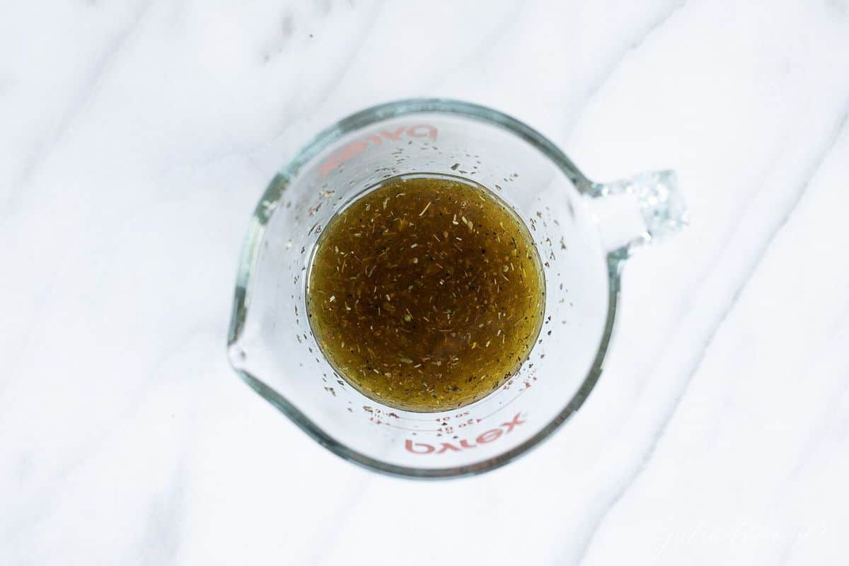 White marble counter top with a pyrex measuring bowl filled with marinade.