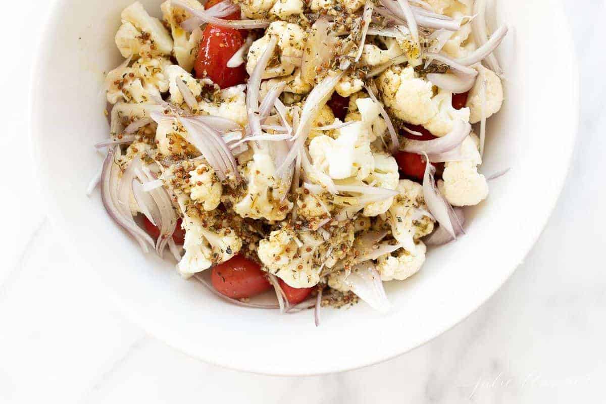 White prep bowl filled with chopped vegetables and seasoning.