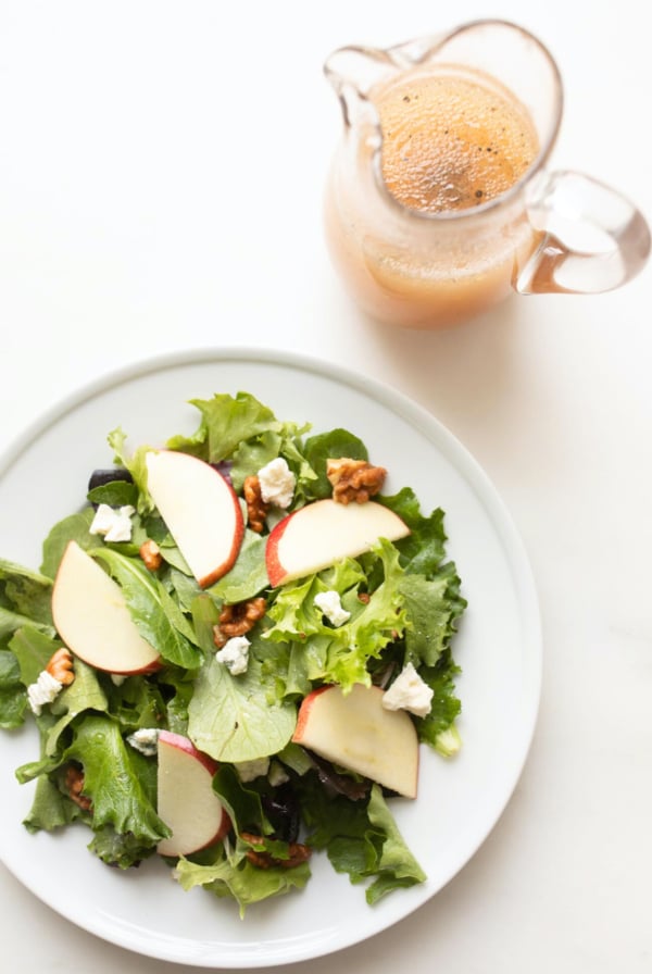 A plate with a salad and a pitcher of apple cider vinegar dressing.
