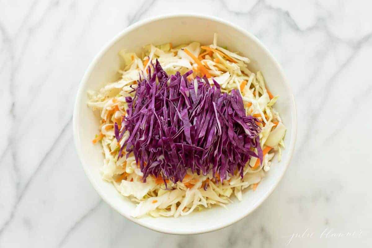 Colorful cabbage salad in a white bowl.
