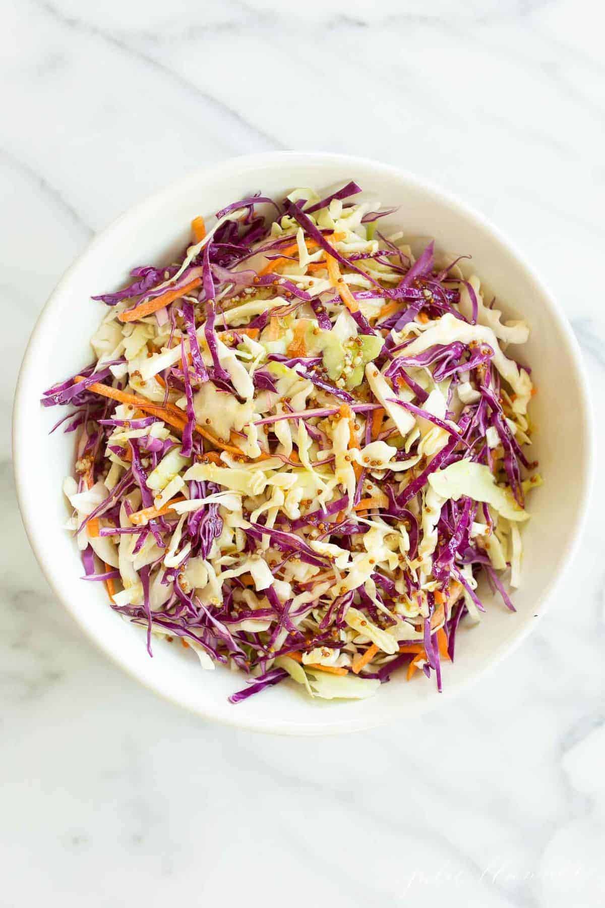 Colorful cabbage salad in a white bowl.