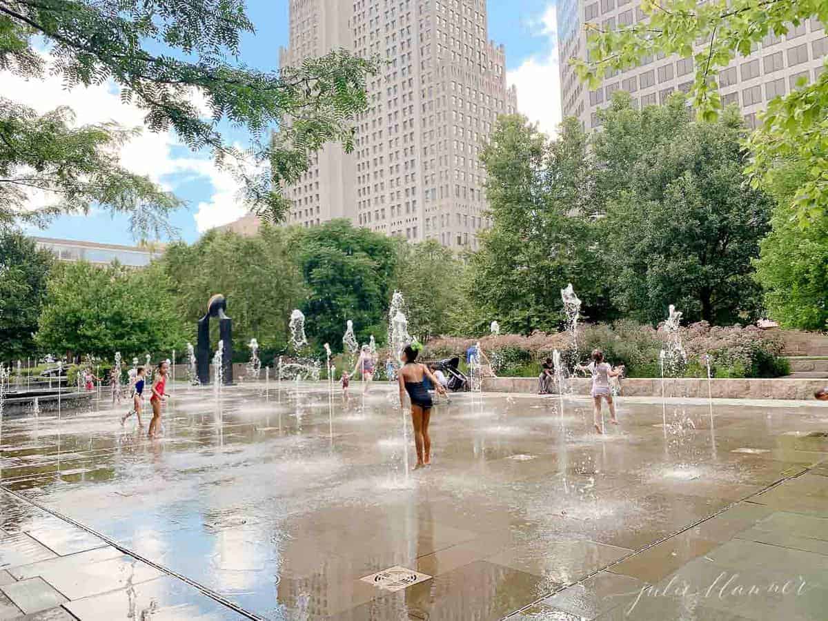 Concrete foundtain/ splash park with St. Louis high rise in background.