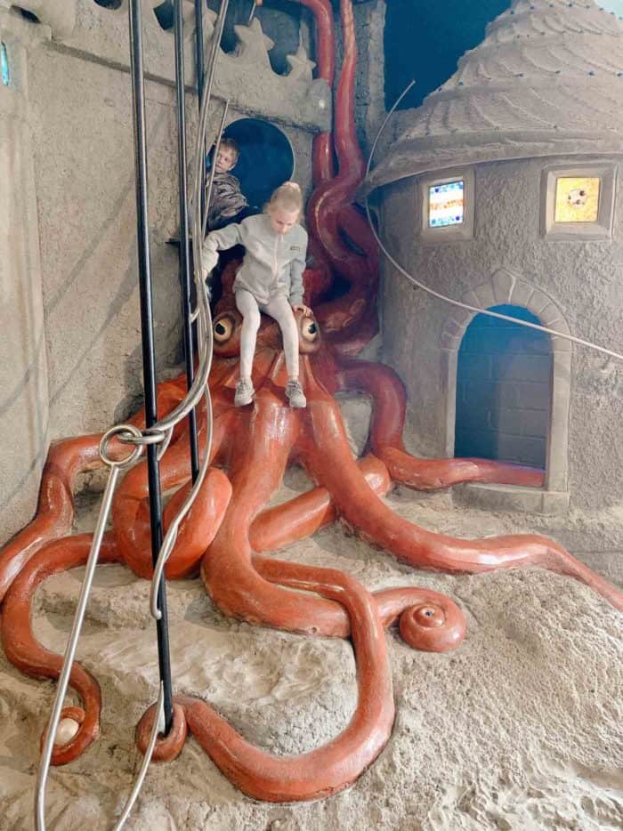 Little girl climbing down giant octopus at the City Museum in St. Louis.
