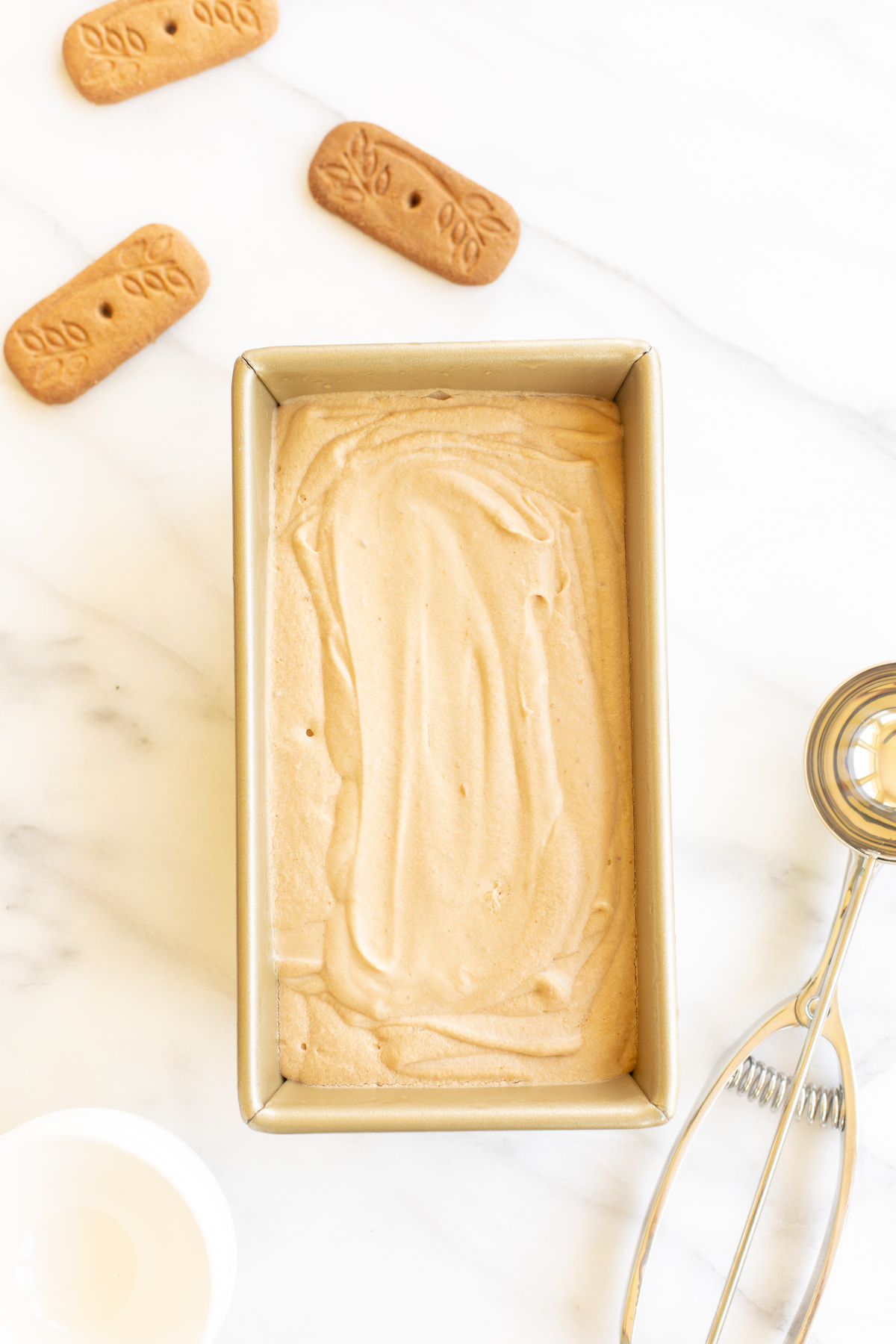 A gold loaf pan full of homemade no churn cookie butter ice cream.