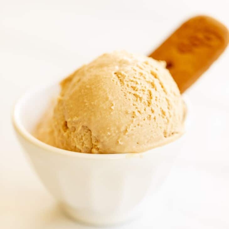 White bowl with two scoops of cookie butter ice cream, on a white surface. #cookiebuttericecream #speculoosicecream