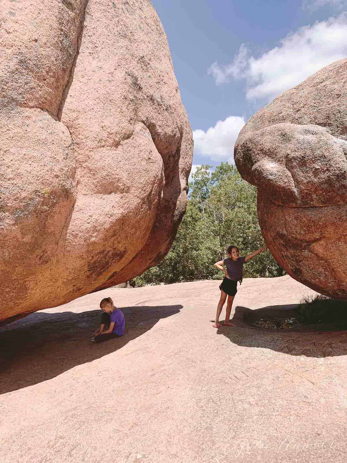 Little girl posing under the Elephant Rocks, giant rocks with a beautiful Missouri tree line view in the background. 