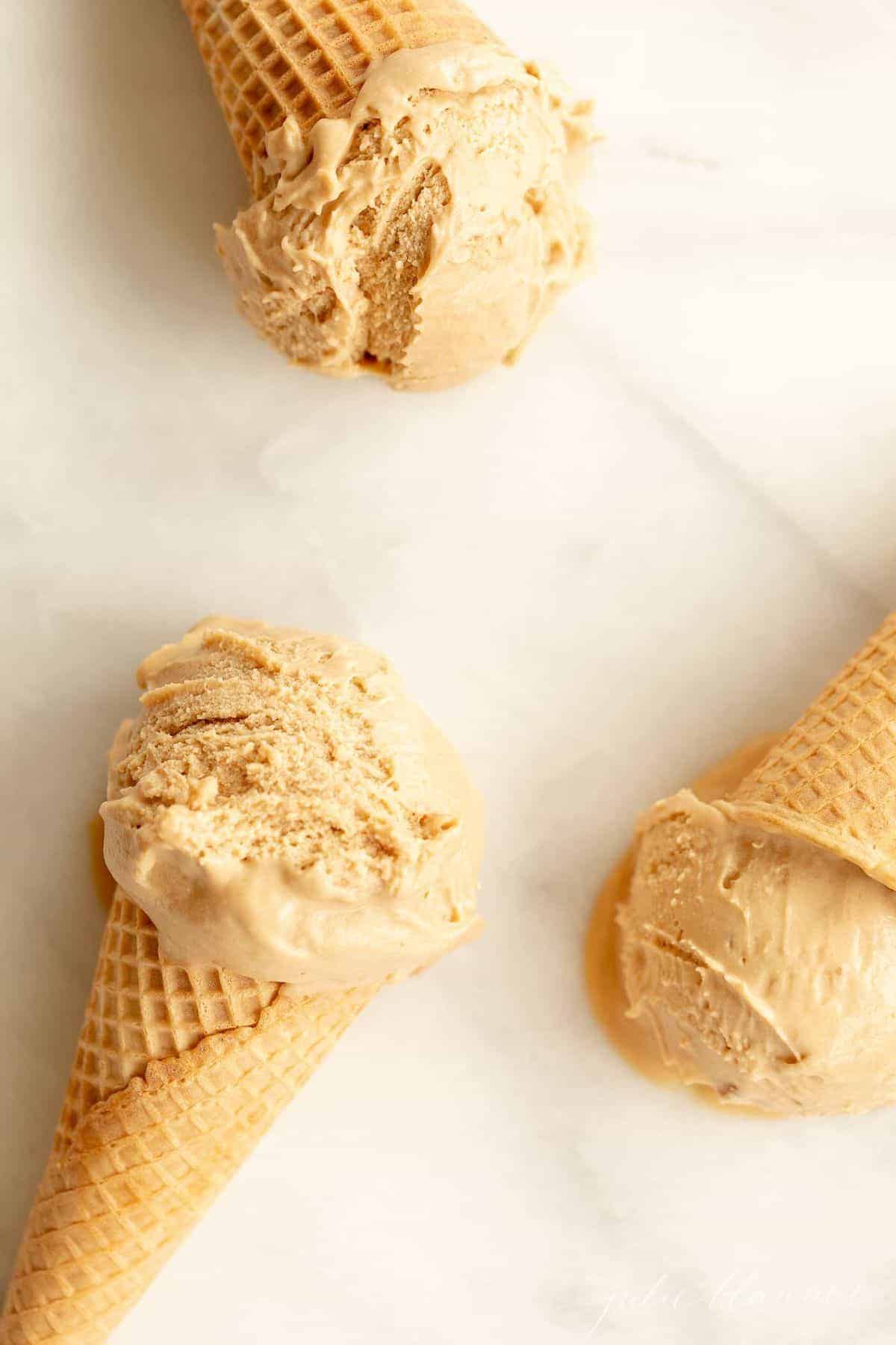 Three waffle ice cream cones on a marble surface, filled with homemade speculoos ice cream. #cookiebuttericecream