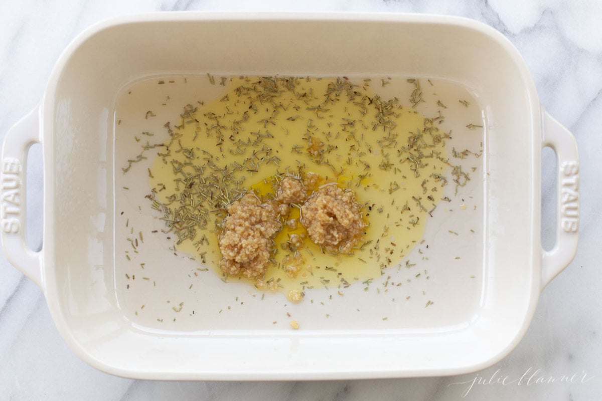 A white baking dish with olive oil and spices.