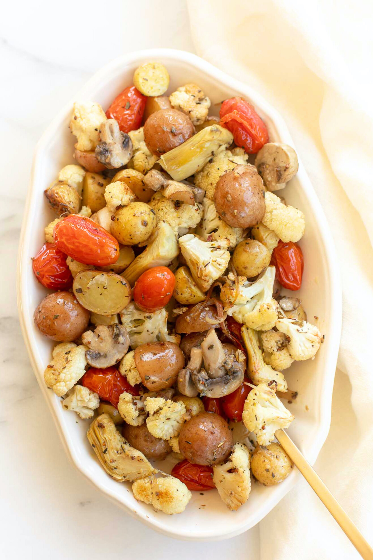A white oval serving dish full of Italian roasted vegetables.