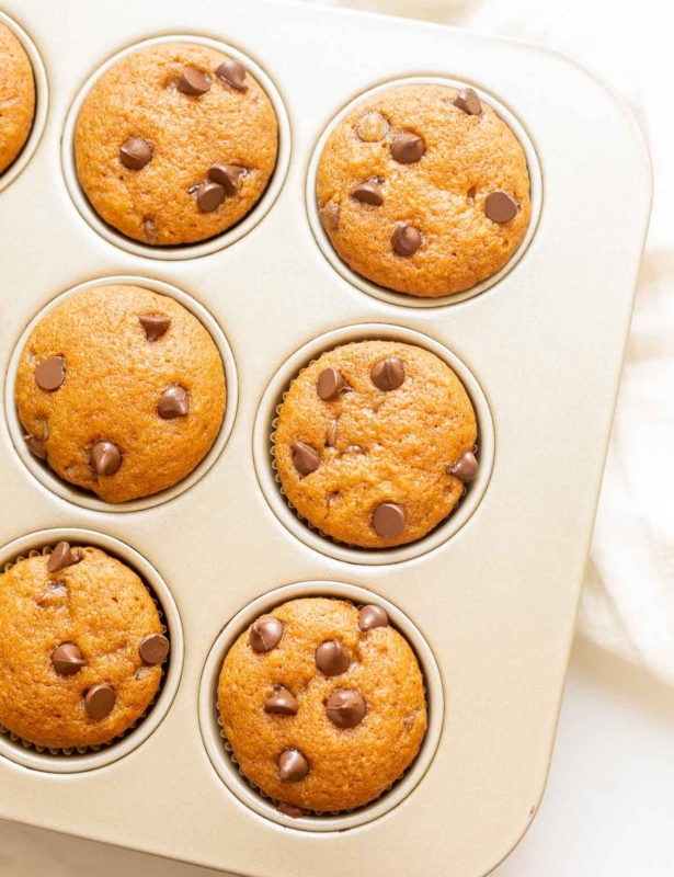 Mini pumpkin chocolate chip muffins in a gold muffin pan.