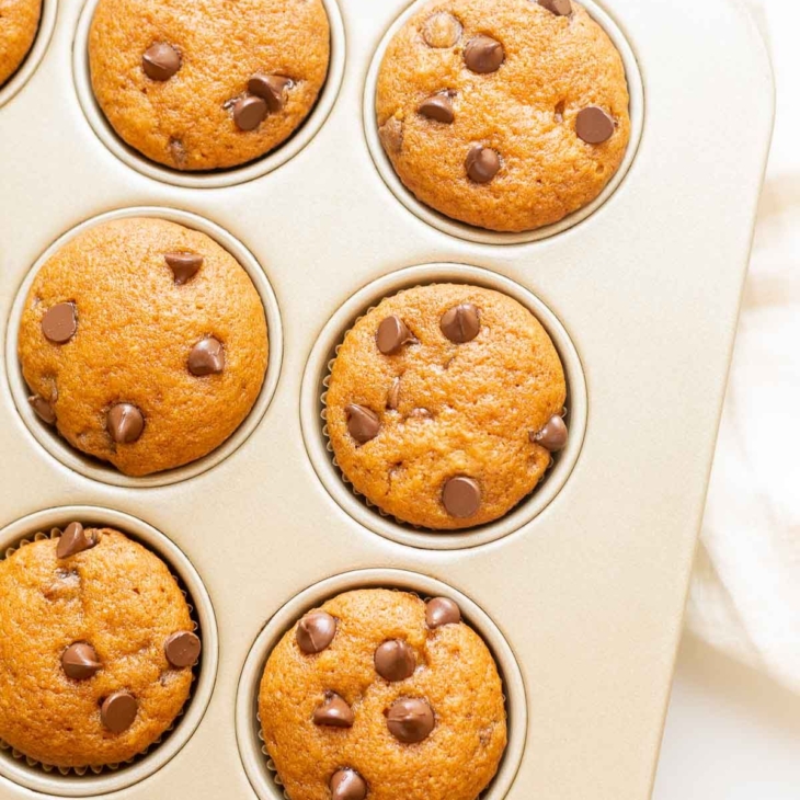 Mini pumpkin chocolate chip muffins in a gold muffin pan.