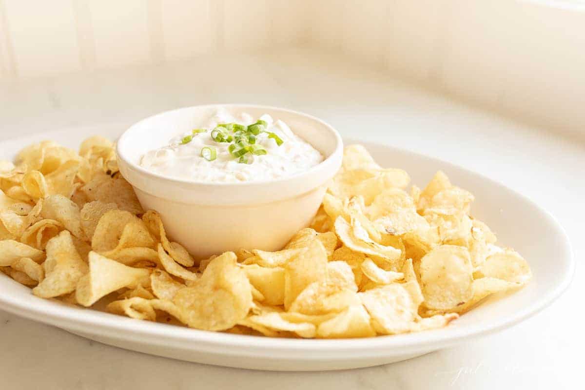 sour cream dip on a platter with chips garnished with green onion