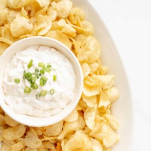 sour cream dip in a bowl surrounded by chips on a platter