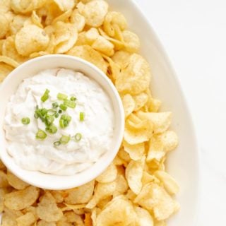 sour cream dip in a bowl surrounded by chips on a platter