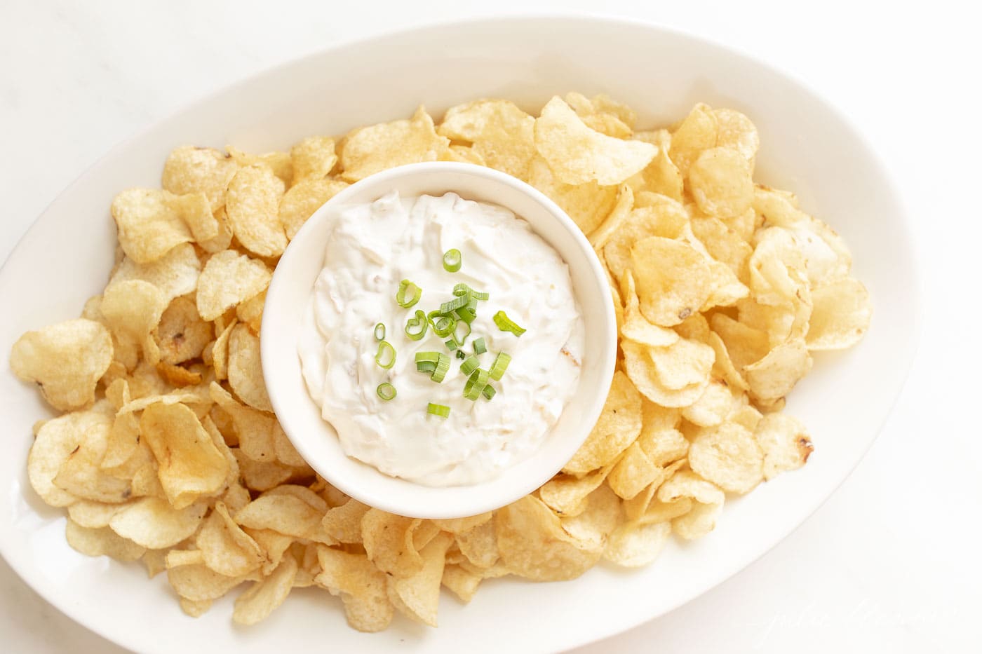 sour cream dip on a platter surrounded by chips