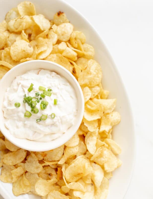 sour cream dip in a bowl surrounded by chips on a platter