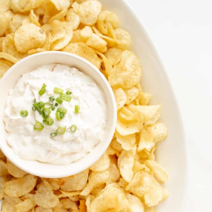 sour cream dip in a bowl surrounded by chips on a platter