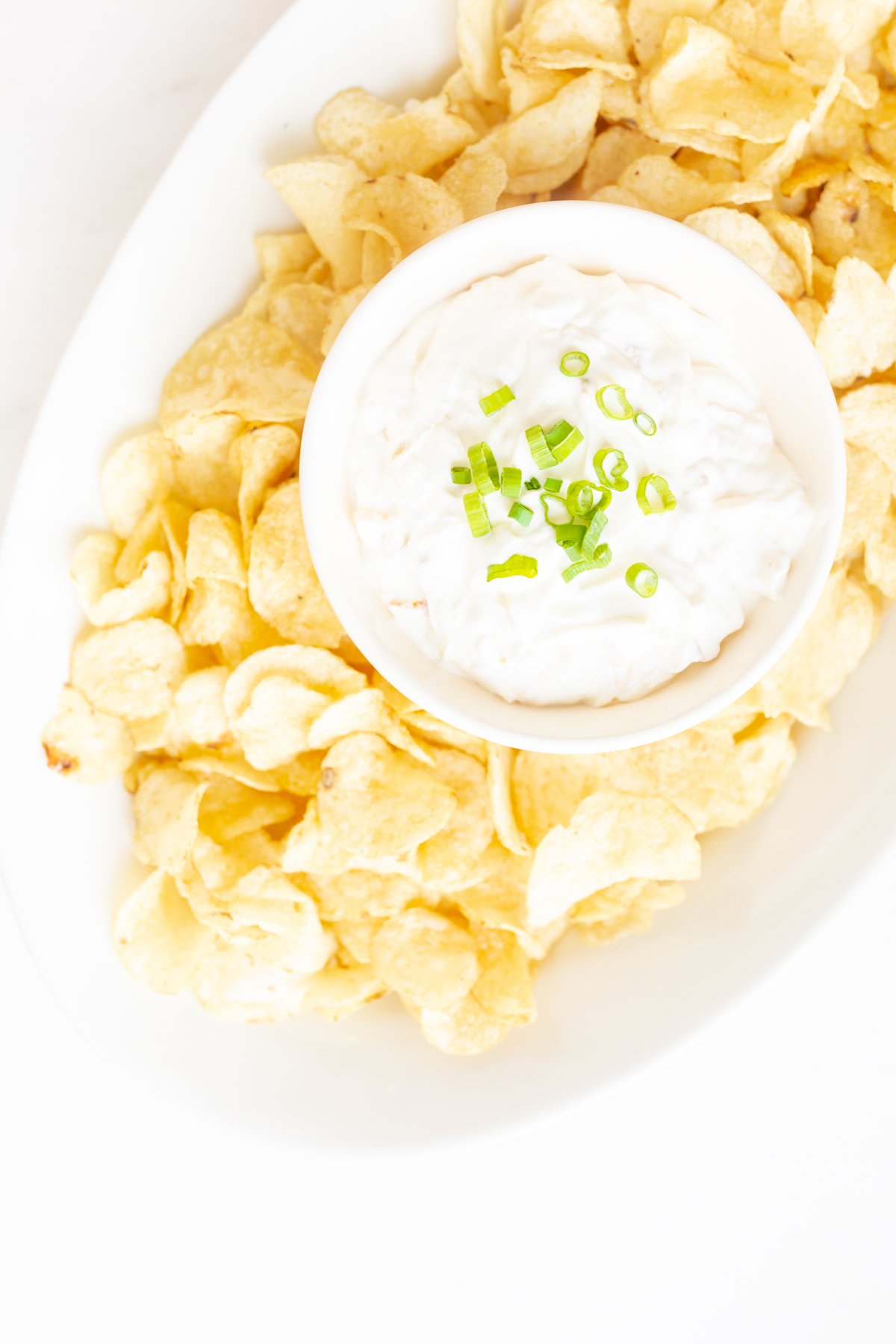 sour cream dip in a bowl surrounded by chips on a platter