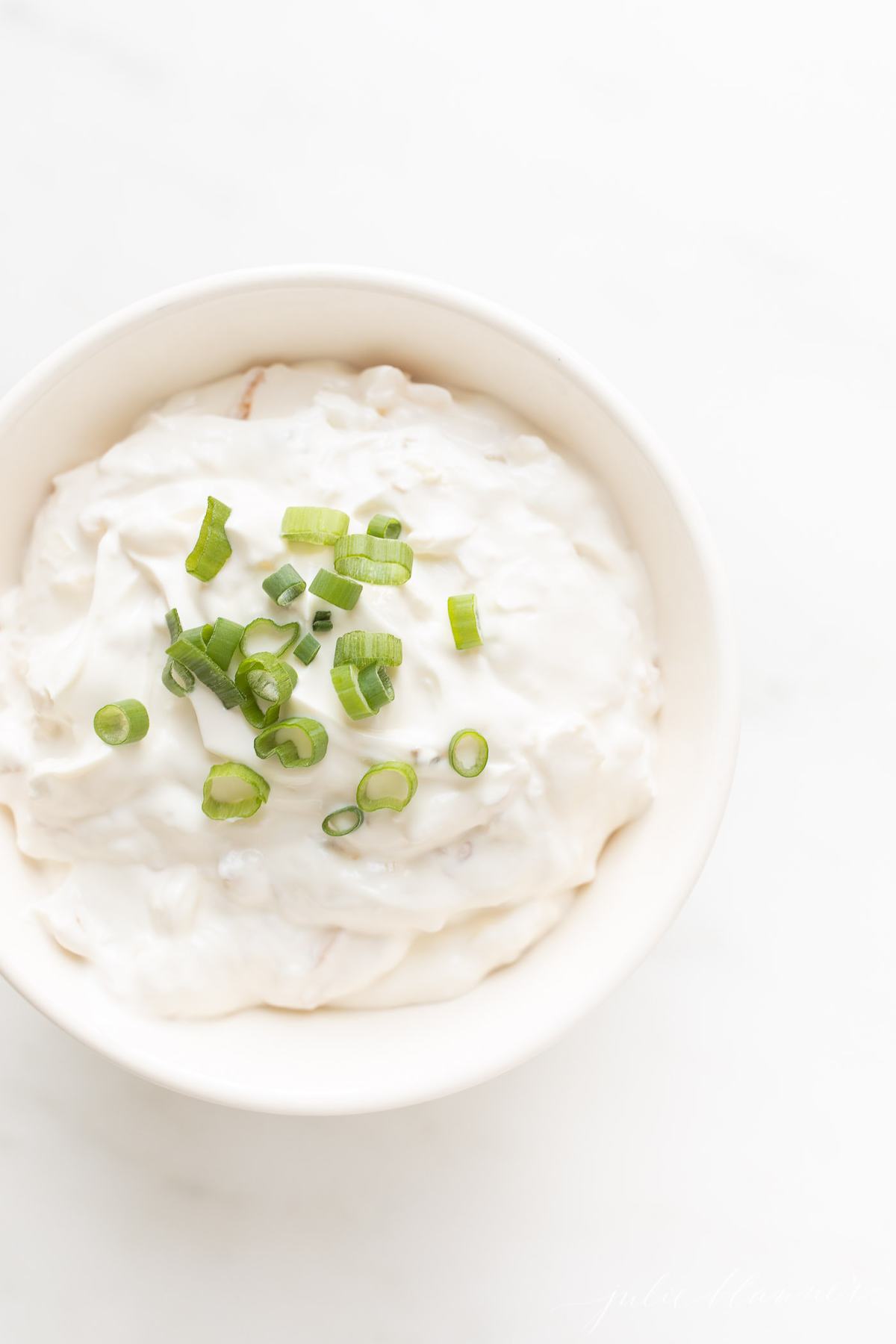 sour cream and onion in a bowl garnished with green onion