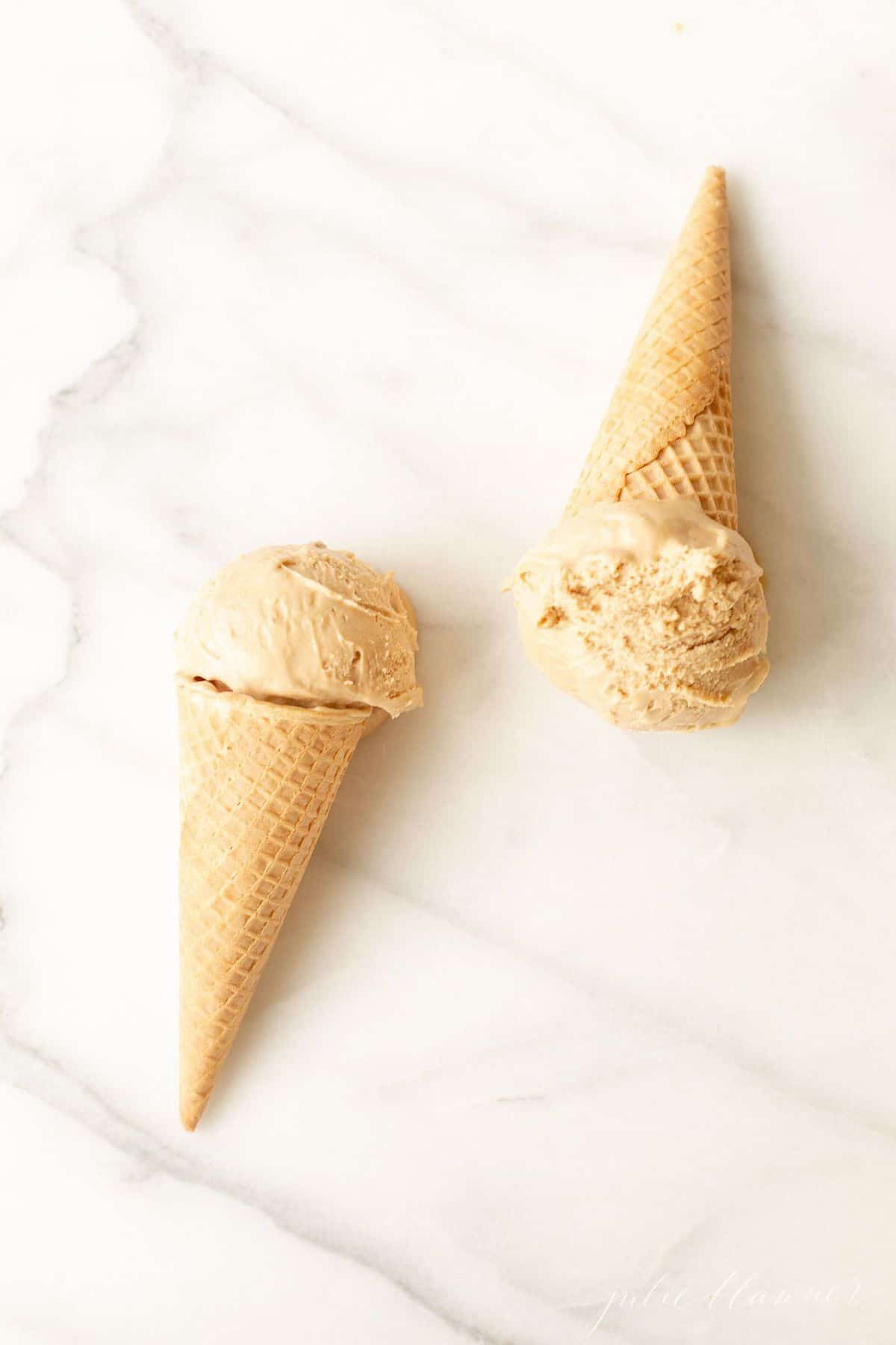 Two waffle ice cream cones on a marble surface, filled with homemade speculoos ice cream. #cookiebuttericecream