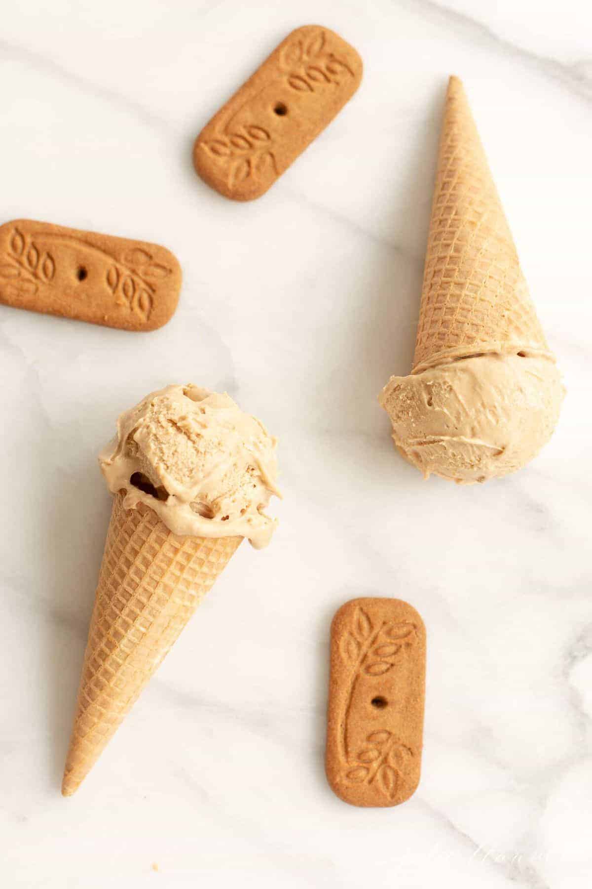 Waffle ice cream cones on a marble surface, filled with homemade speculoos ice cream. #cookiebuttericecream