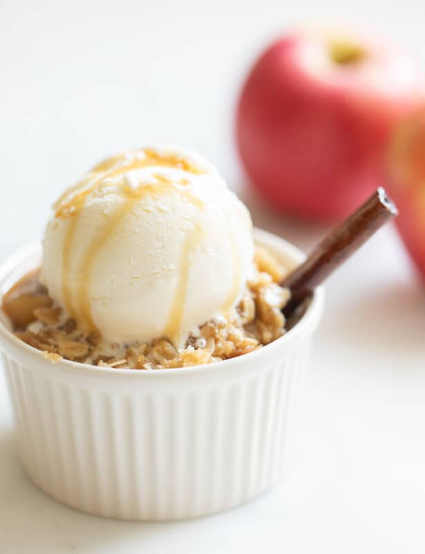 apple crisp with ice cream and caramel sauce on top and apple in background