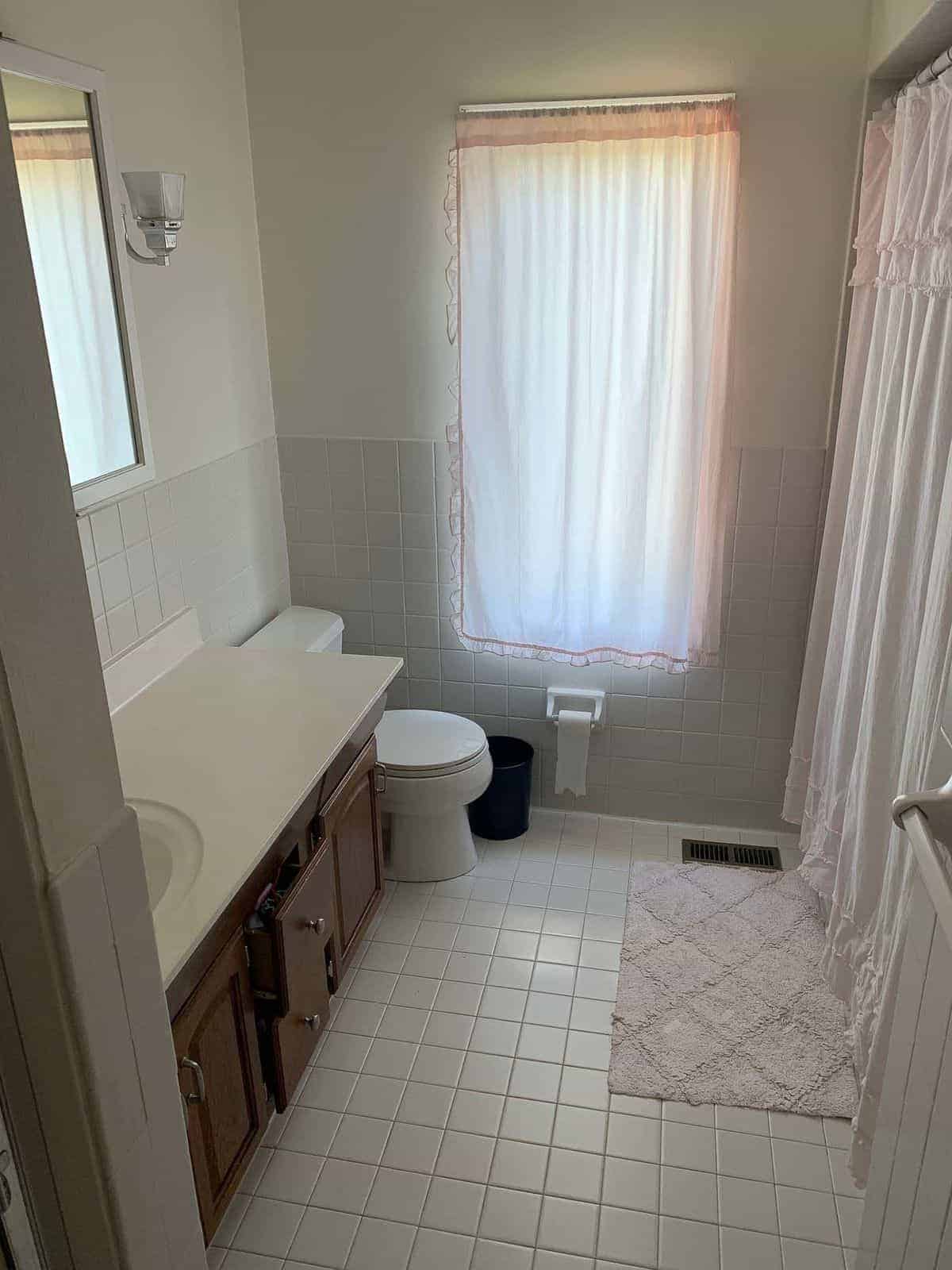 Dated 70's bathroom with dark cabinet, dated tile and no lighting. 