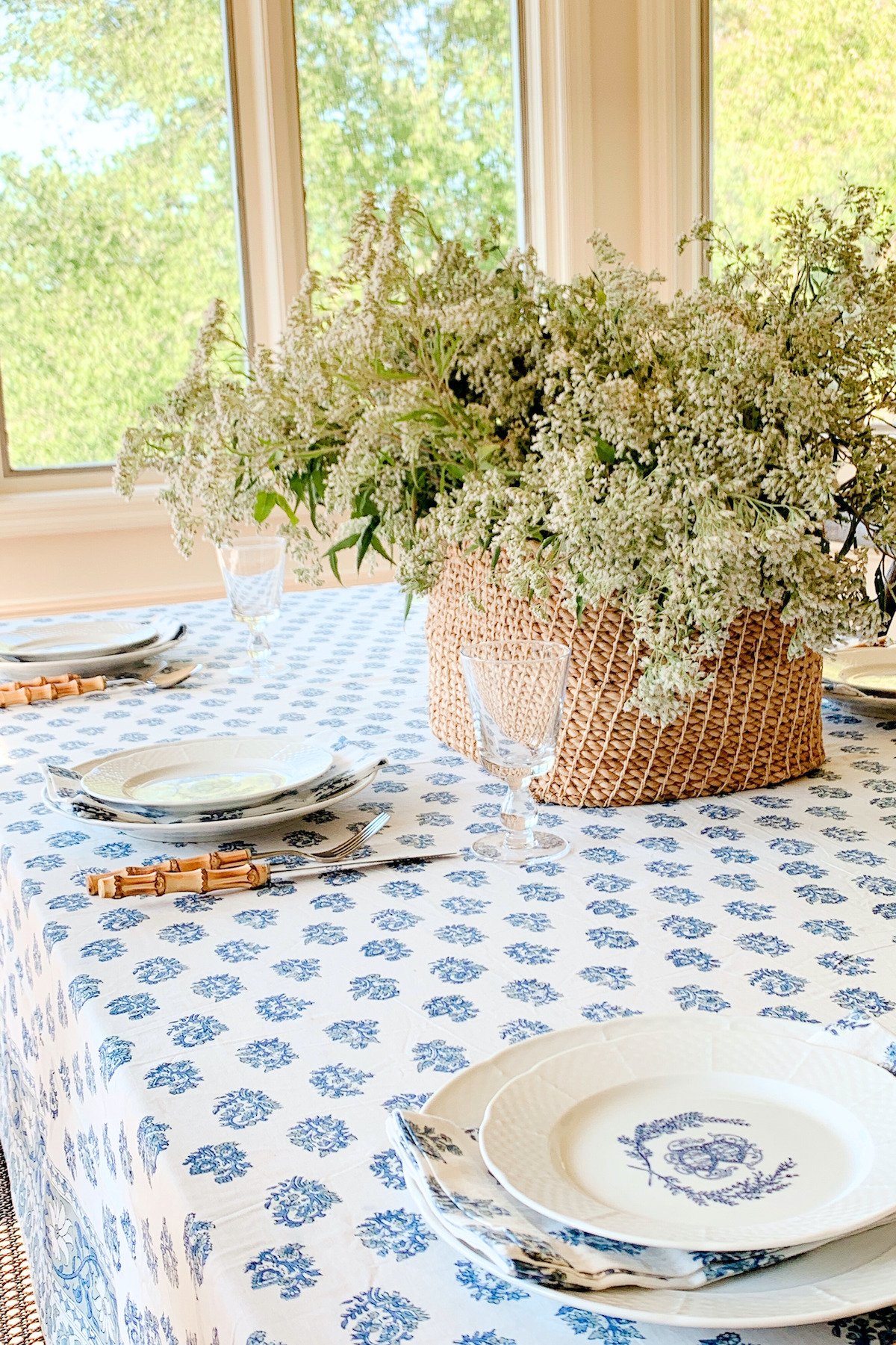 A blue and white block print tablecloth on a table surrounded by wood chairs.