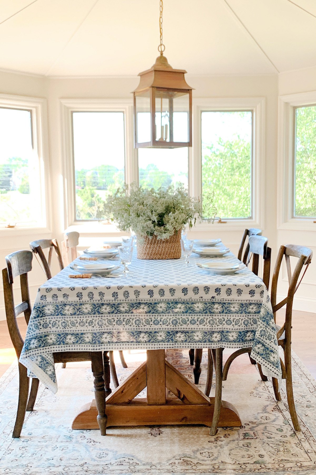 A dining room table with chairs and a blue block print tablecloth.