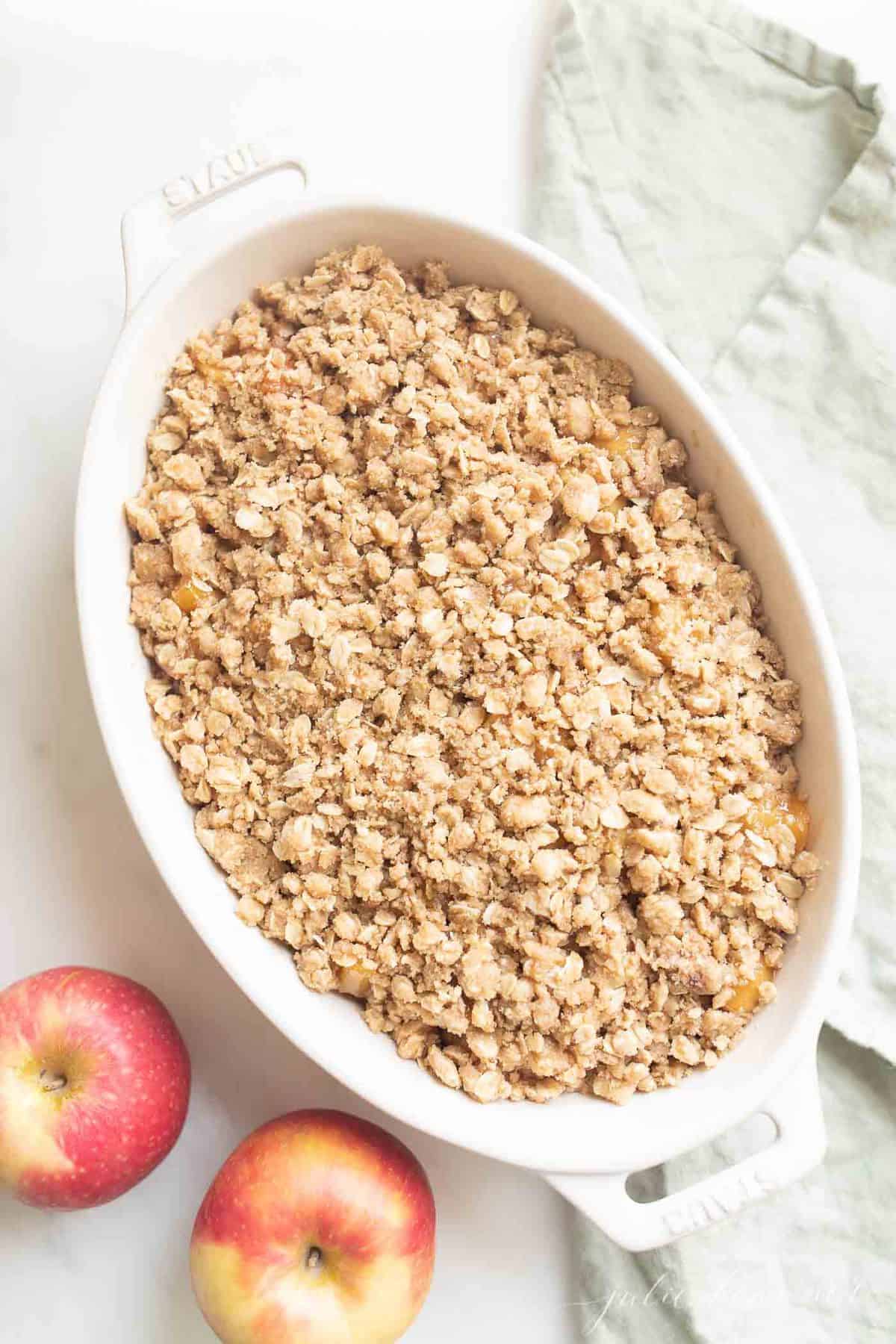 apple crisp in baking dish with apples to the side