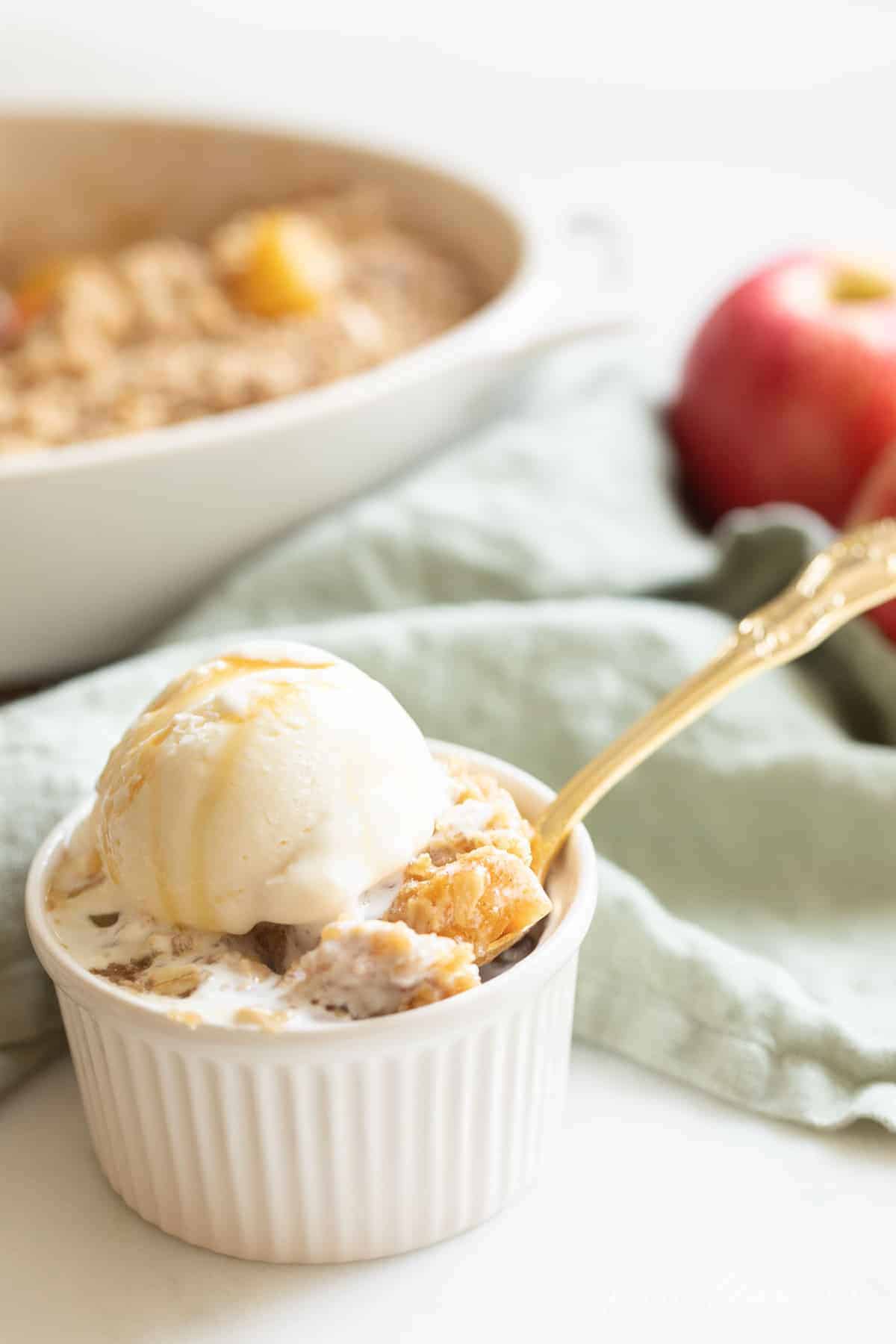 apple crisp in a bowl with ice cream and spoon
