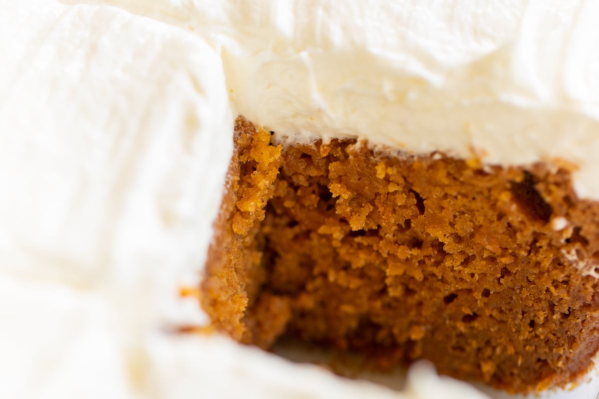 A slice of pumpkin cake with cream cheese frosting.