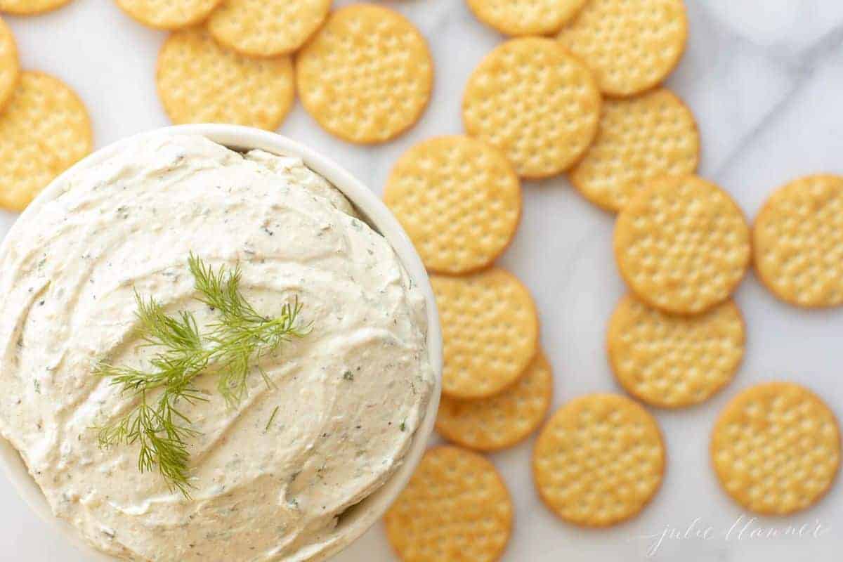 Boursin cheese spread on a marble counter top with crackers around it. 