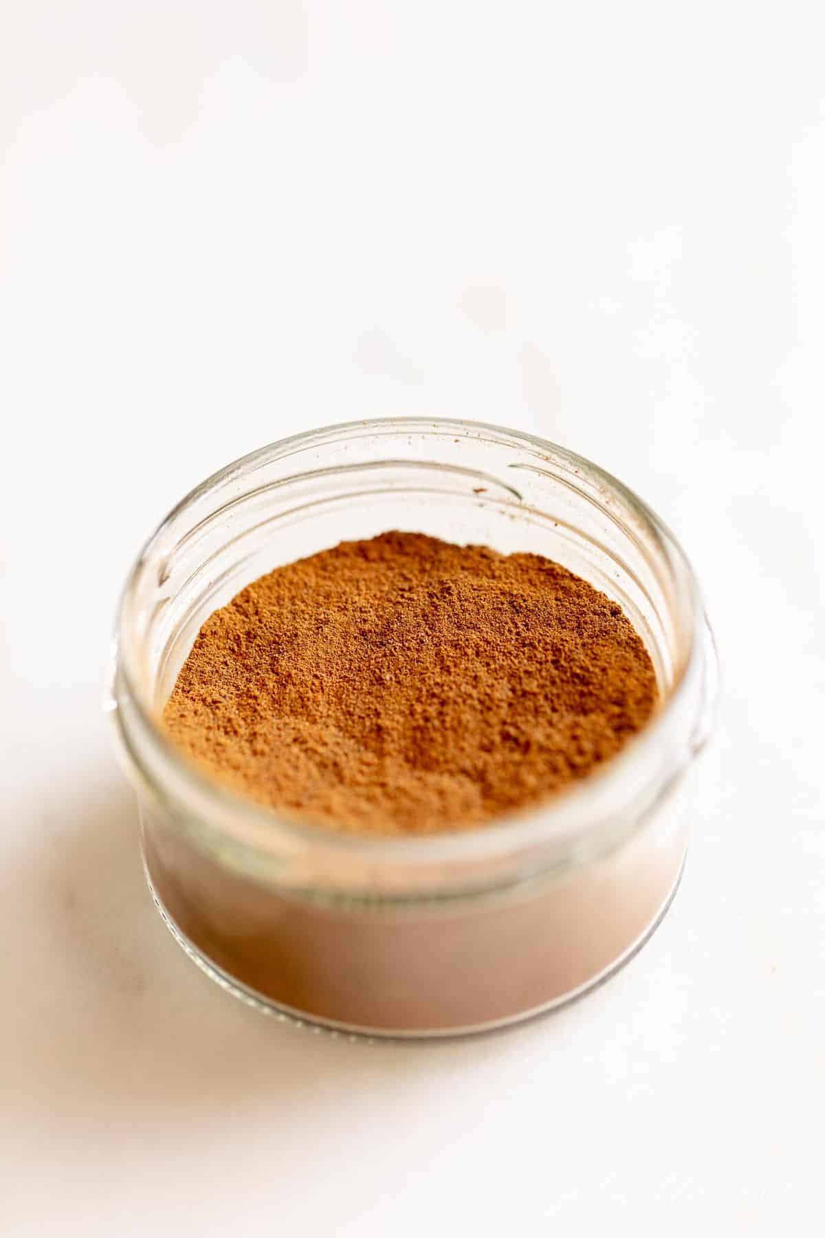 Clear jar of spices on a white counter top.