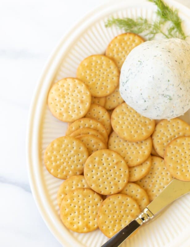 Boursin cheese ball on a cream platter with crackers and a cheese spreader. #boursincheese