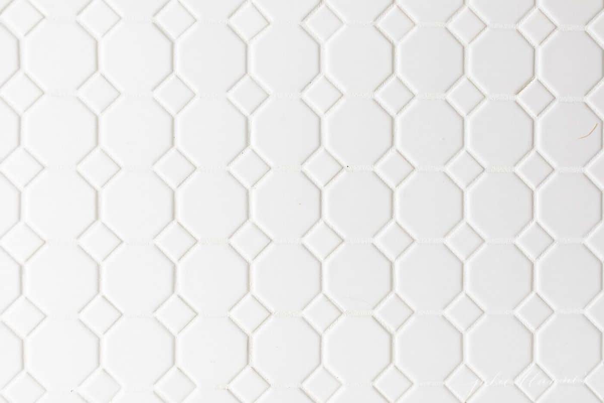 close-up shot of white honeycomb floor tile and white grout. 