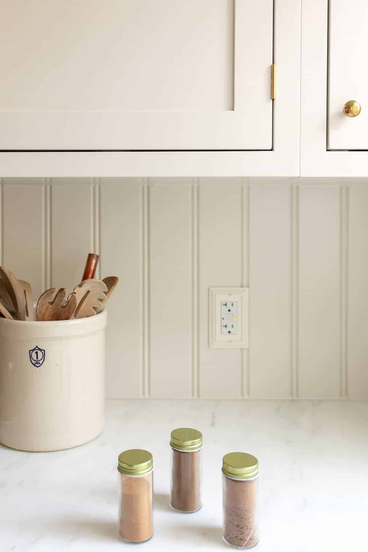 A cream kitchen with spice jars on the countertop.