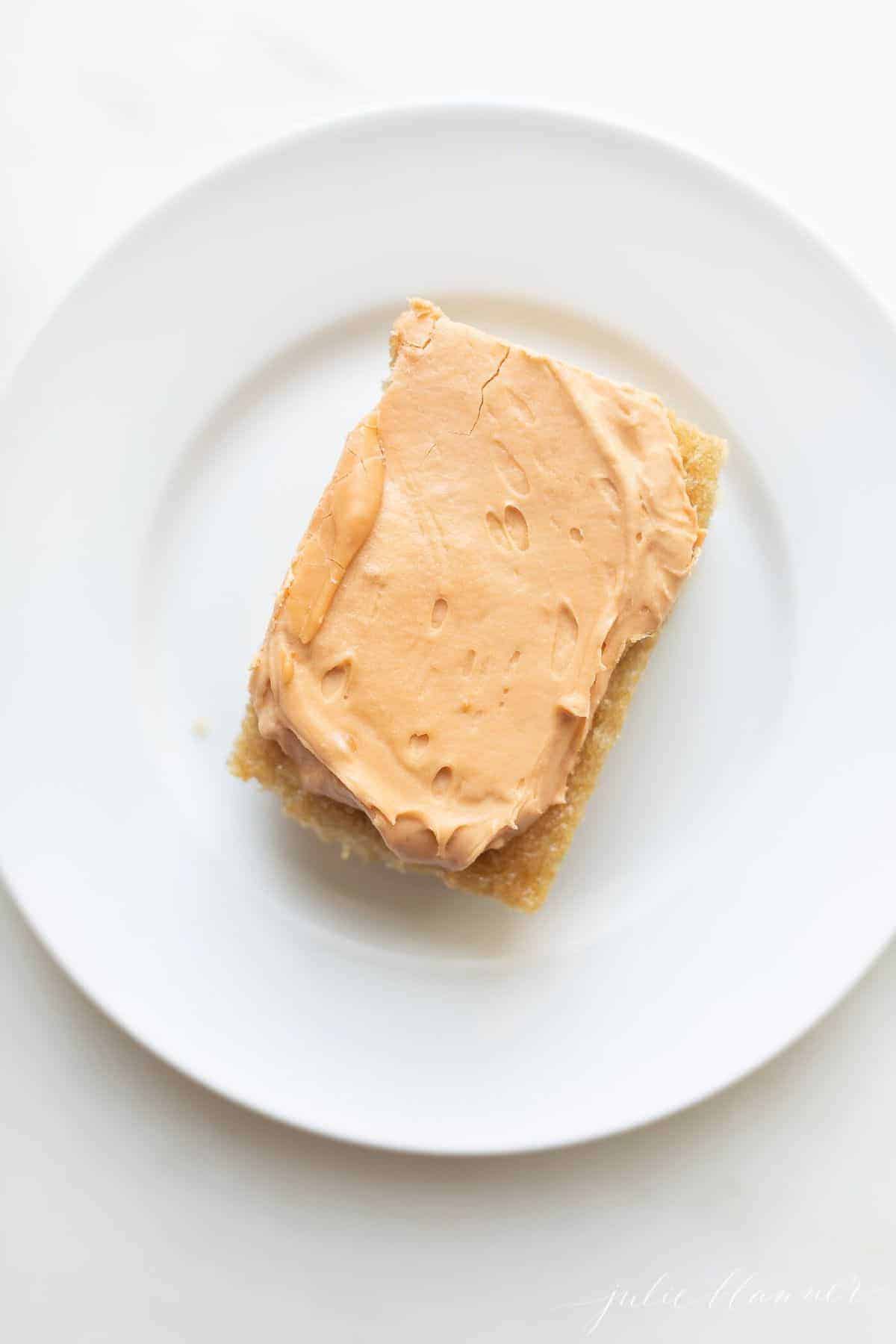A piece of frosted Butterscotch cake on a white plate.